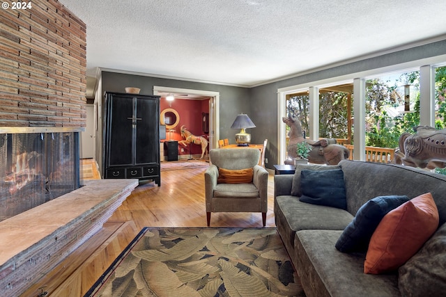 living room featuring a fireplace, wood-type flooring, a wealth of natural light, and a textured ceiling