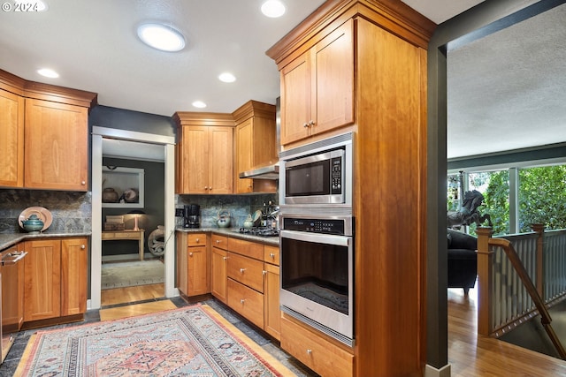 kitchen with tasteful backsplash, light hardwood / wood-style flooring, appliances with stainless steel finishes, and a textured ceiling