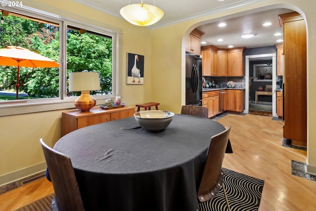 dining area with light wood-type flooring and ornamental molding