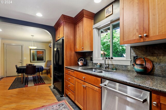 kitchen featuring tasteful backsplash, sink, black refrigerator, light hardwood / wood-style floors, and stainless steel dishwasher