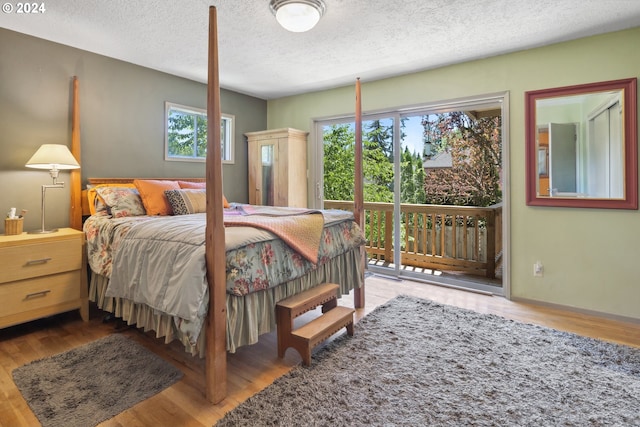 bedroom featuring access to exterior, a textured ceiling, and hardwood / wood-style floors