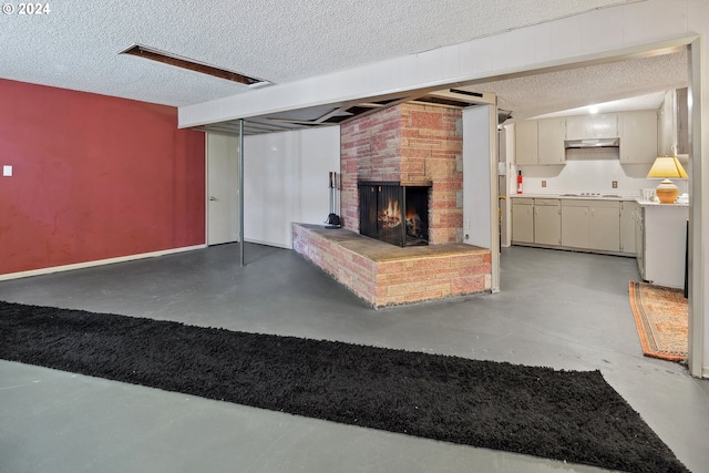 living room featuring a fireplace, concrete flooring, brick wall, and a textured ceiling