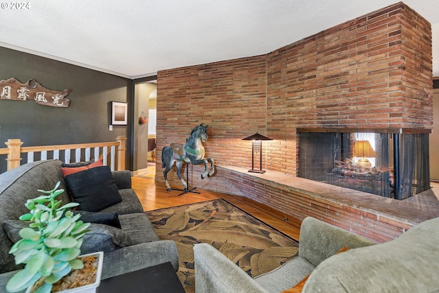 living room featuring light hardwood / wood-style floors, a brick fireplace, brick wall, and crown molding