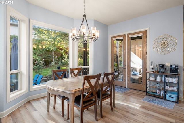 dining space with french doors, light hardwood / wood-style flooring, and a chandelier