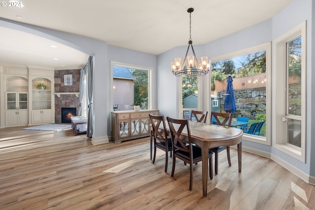 dining room featuring light hardwood / wood-style floors, a large fireplace, and a notable chandelier