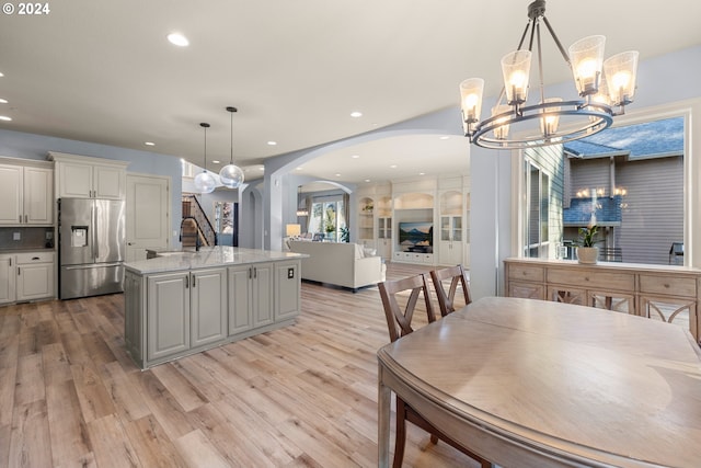 kitchen featuring pendant lighting, light hardwood / wood-style flooring, an island with sink, and stainless steel fridge