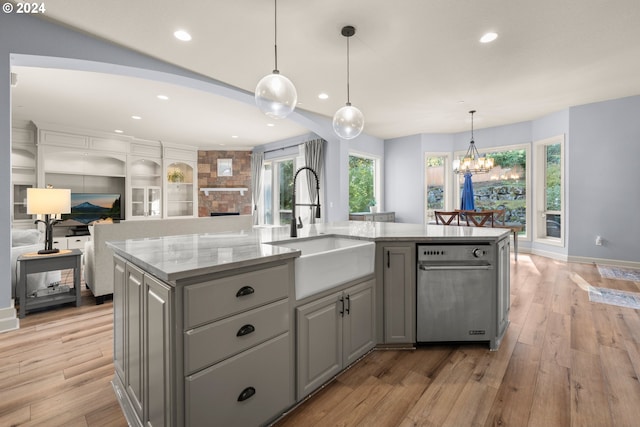 kitchen with pendant lighting, sink, an island with sink, and light hardwood / wood-style floors