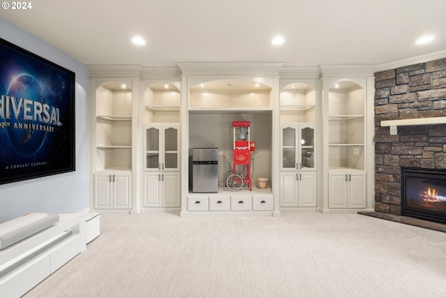 unfurnished living room featuring built in shelves, light colored carpet, crown molding, and a fireplace