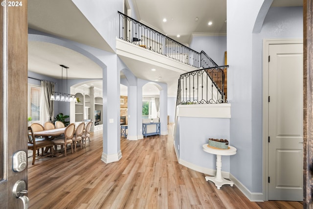 entryway with hardwood / wood-style floors, an inviting chandelier, and ornamental molding