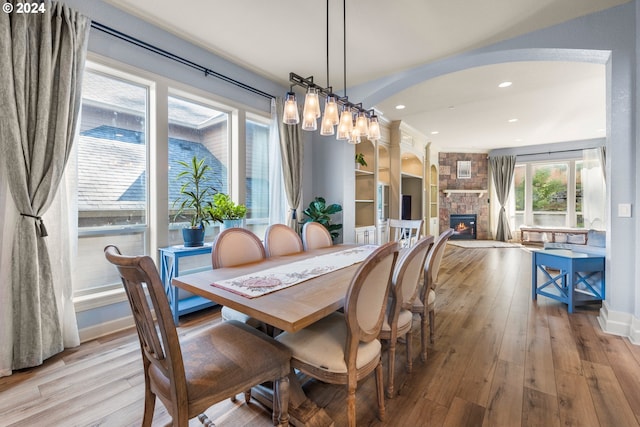 dining room featuring a stone fireplace and light hardwood / wood-style floors