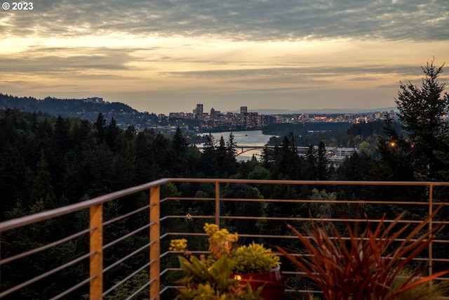 balcony at dusk featuring a water view