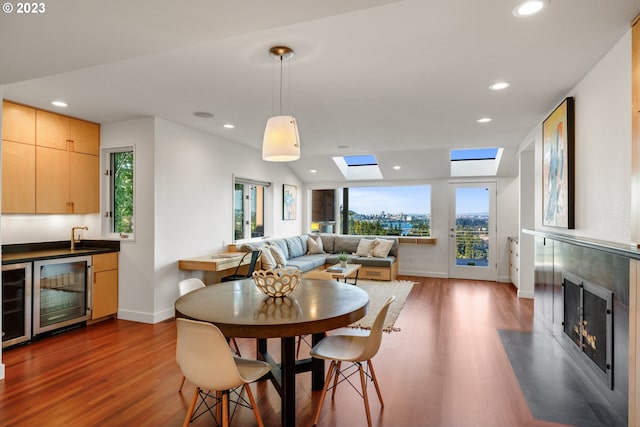 dining area featuring a skylight, a wealth of natural light, beverage cooler, wood-type flooring, and a high end fireplace