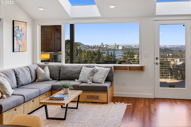 living room featuring dark hardwood / wood-style flooring, a wealth of natural light, and vaulted ceiling with skylight