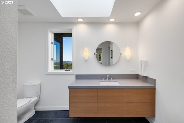 bathroom with tile patterned floors, vanity, a skylight, and toilet