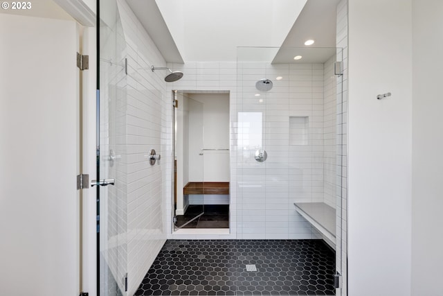 bathroom with a tile shower, tile patterned flooring, and tile walls