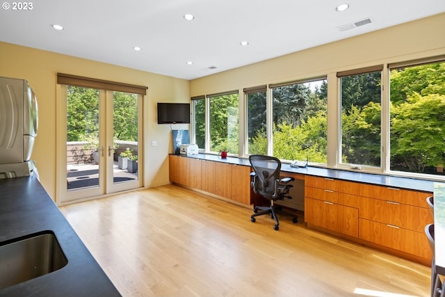 office area featuring washer / dryer, light hardwood / wood-style floors, and a wealth of natural light