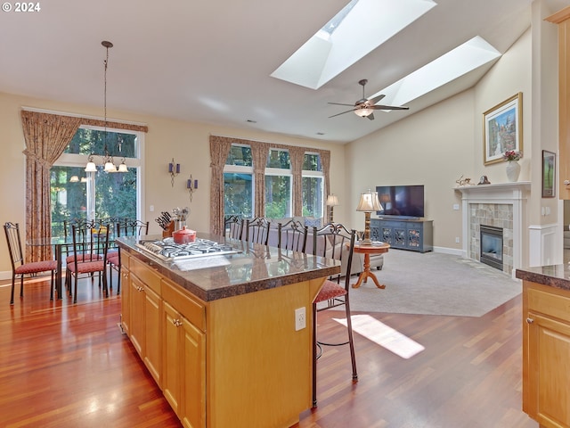 kitchen featuring a center island, a tile fireplace, hanging light fixtures, lofted ceiling with skylight, and a breakfast bar area