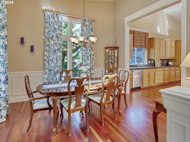 dining room with an inviting chandelier, a decorative wall, wainscoting, and wood finished floors