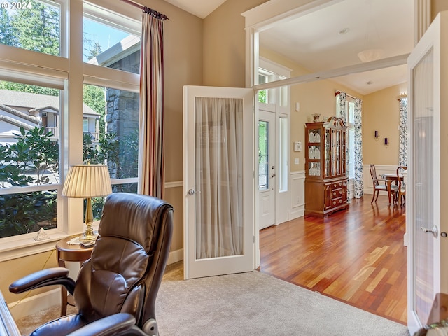 carpeted home office with wainscoting and wood finished floors