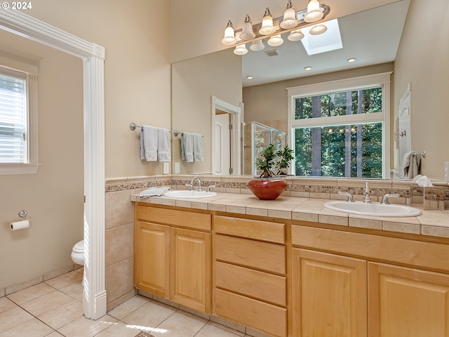 bathroom with a skylight, an enclosed shower, toilet, tile patterned floors, and vanity