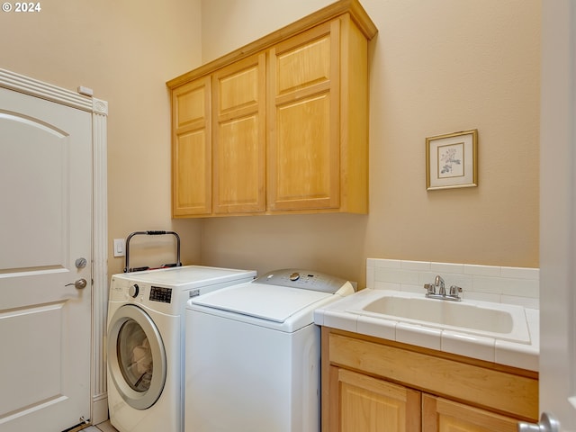 clothes washing area with independent washer and dryer, a sink, and cabinet space