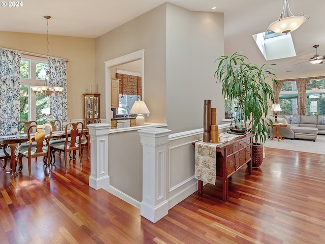 hall featuring a chandelier, vaulted ceiling with skylight, and wood-type flooring