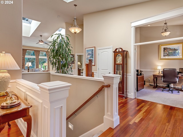 hallway with a skylight, an upstairs landing, and wood finished floors