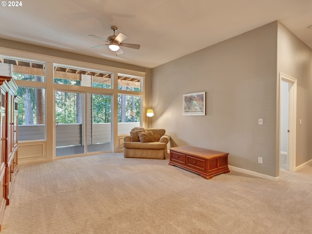 living area with a ceiling fan, baseboards, light colored carpet, and plenty of natural light