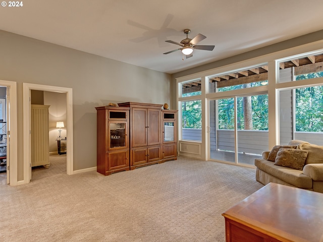 living room with a ceiling fan, baseboards, plenty of natural light, and light carpet