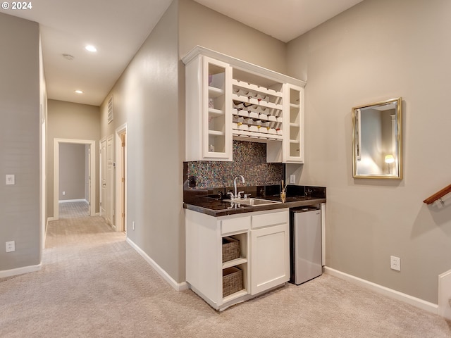 bar with decorative backsplash, sink, light colored carpet, white cabinets, and stainless steel refrigerator