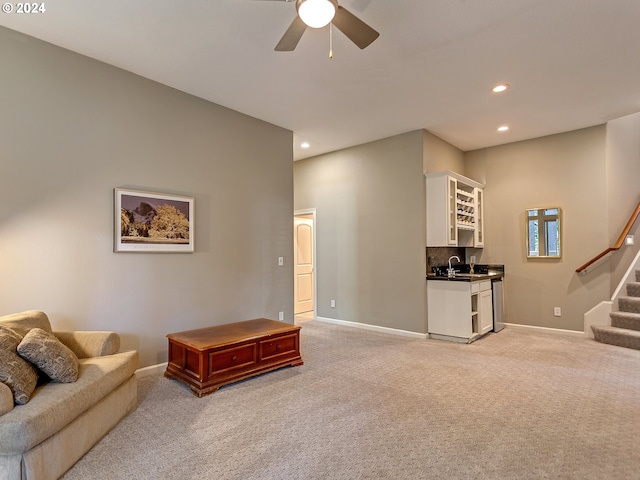 living area with stairway, baseboards, and light carpet