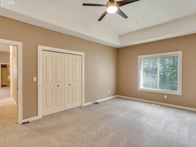 unfurnished bedroom with a closet, light colored carpet, and ceiling fan