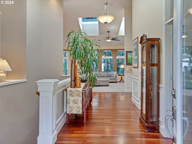 foyer entrance with ceiling fan, a skylight, a high ceiling, and hardwood / wood-style floors