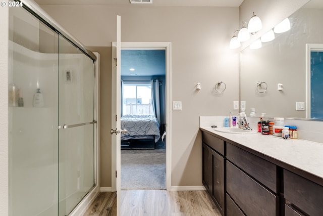 bathroom with hardwood / wood-style flooring, vanity, and walk in shower