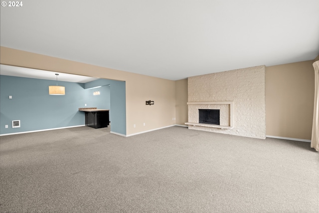 unfurnished living room with carpet floors and a large fireplace