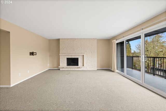 unfurnished living room with carpet flooring and a large fireplace