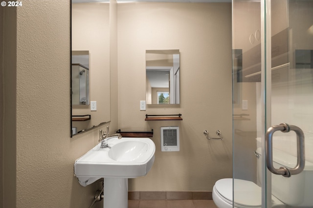 bathroom featuring tile patterned flooring, heating unit, toilet, and a shower with door