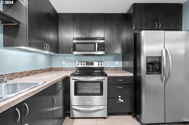 kitchen with decorative backsplash, light tile patterned floors, stainless steel appliances, and sink