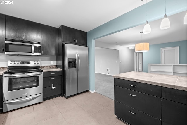 kitchen featuring pendant lighting, light tile patterned floors, and stainless steel appliances