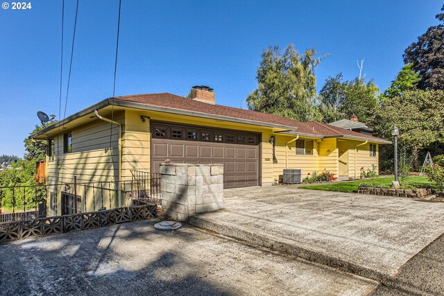 ranch-style home featuring cooling unit and a garage