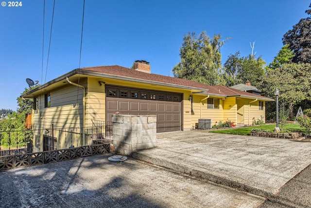 ranch-style house with a garage, central AC, driveway, and a chimney