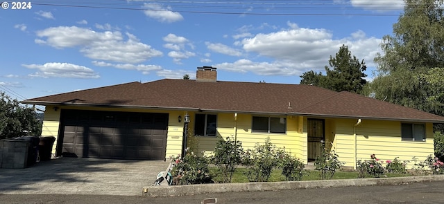 ranch-style house with a chimney, driveway, roof with shingles, and an attached garage