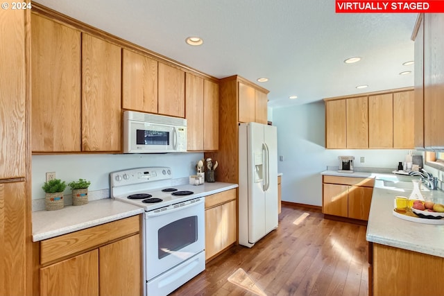 kitchen featuring recessed lighting, light countertops, light wood-style floors, a sink, and white appliances