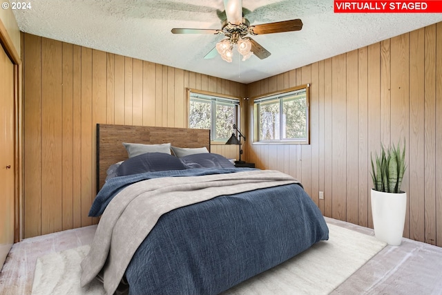 bedroom with a textured ceiling, wood walls, and carpet