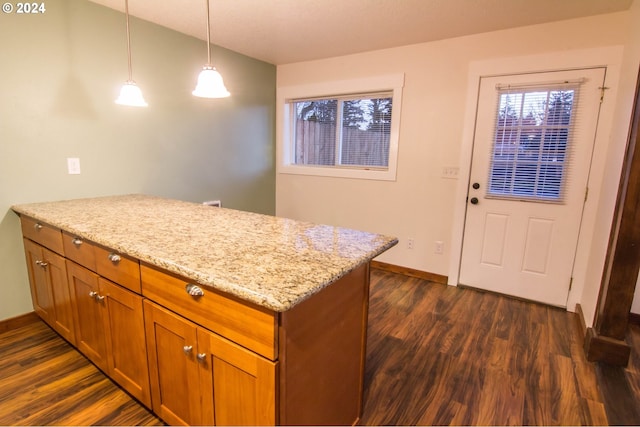 kitchen featuring light stone counters, decorative light fixtures, and dark hardwood / wood-style flooring