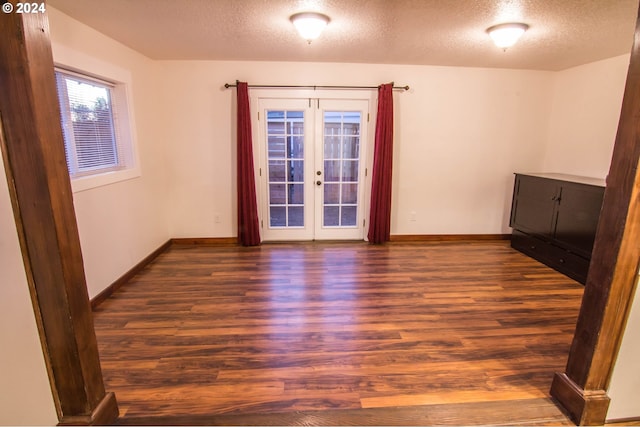 unfurnished room featuring a textured ceiling, hardwood / wood-style floors, and french doors