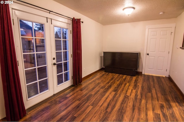 empty room featuring a textured ceiling, french doors, and dark hardwood / wood-style floors