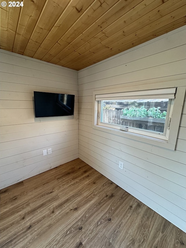 unfurnished room with wooden ceiling, hardwood / wood-style flooring, and wood walls