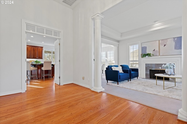 living room featuring ornamental molding, decorative columns, light hardwood / wood-style flooring, and a healthy amount of sunlight