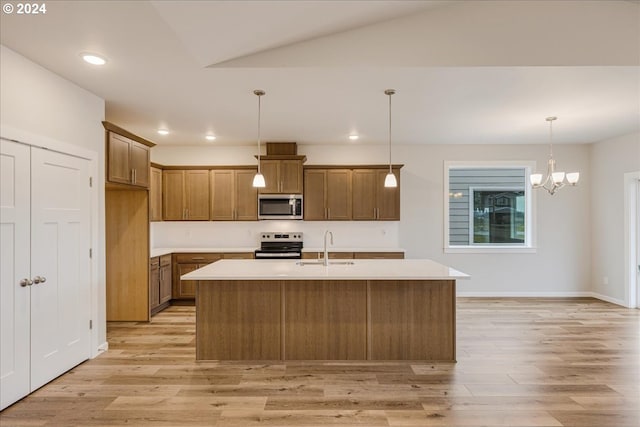 kitchen featuring stainless steel appliances, sink, light hardwood / wood-style flooring, hanging light fixtures, and an island with sink